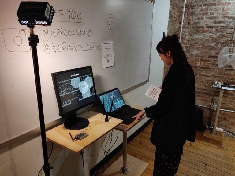 A girl looking at the project with a wireless antenna, monitor, and laptop on a table